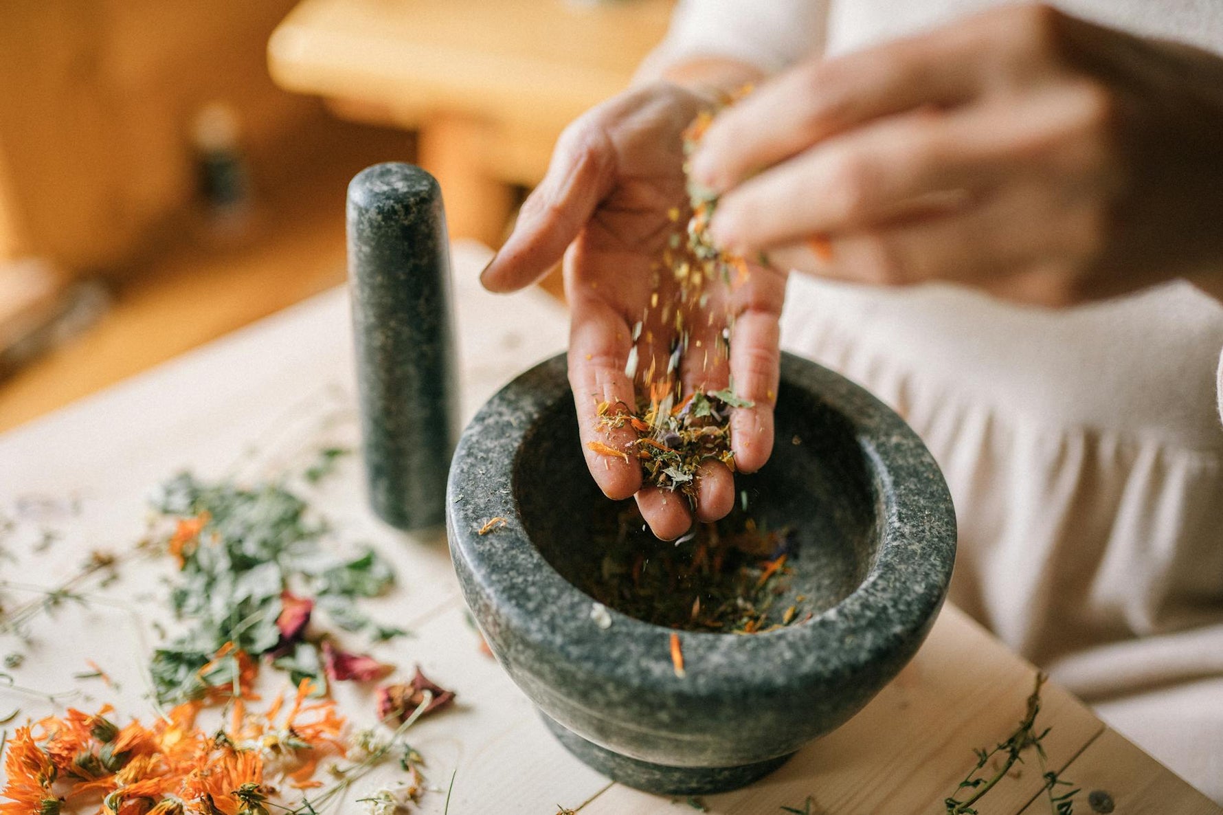 Close-up of herbs being prepared in a mortar and pestle, showcasing natural remedy techniques
